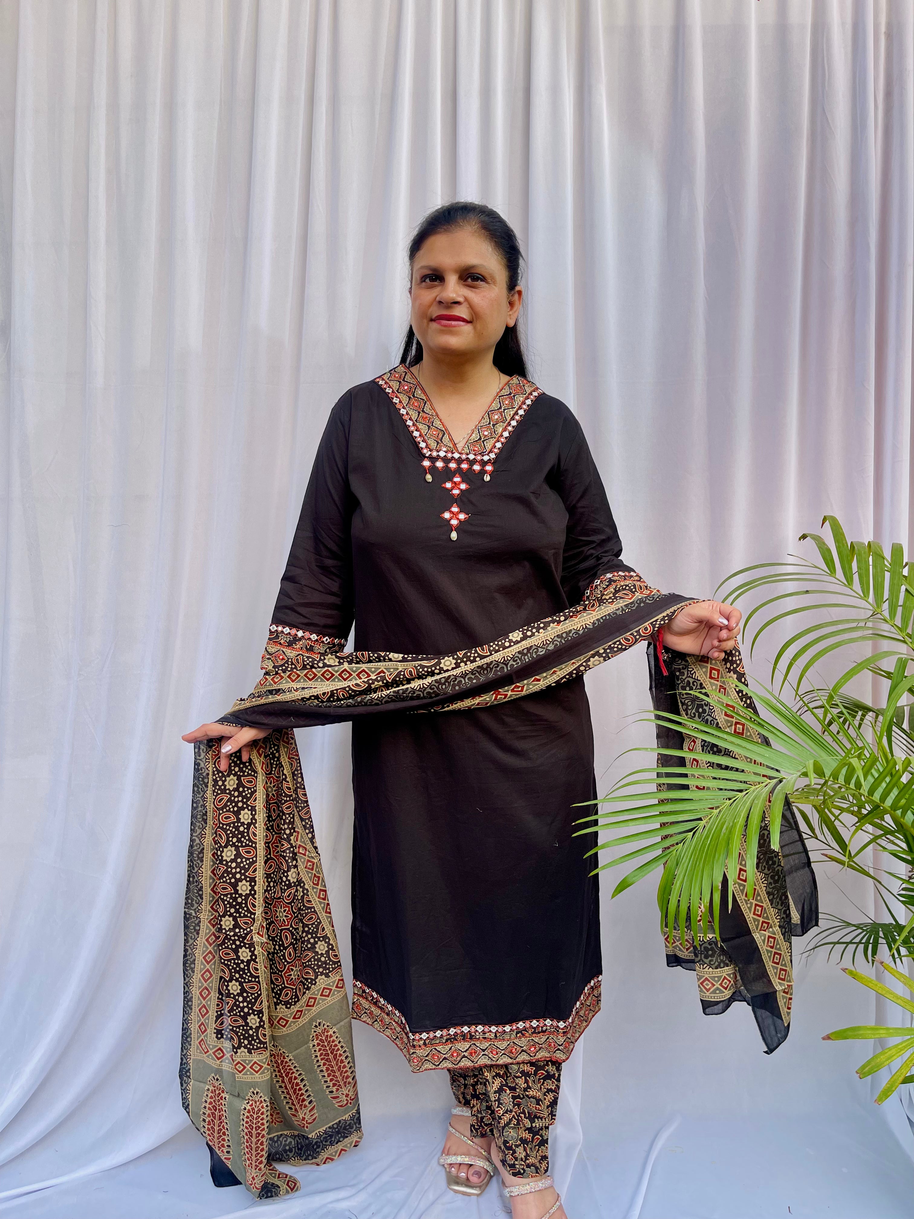 Woman wearing a black ethnic printed kurta set with matching pants and dupatta, featuring traditional motifs and a V-neck design.