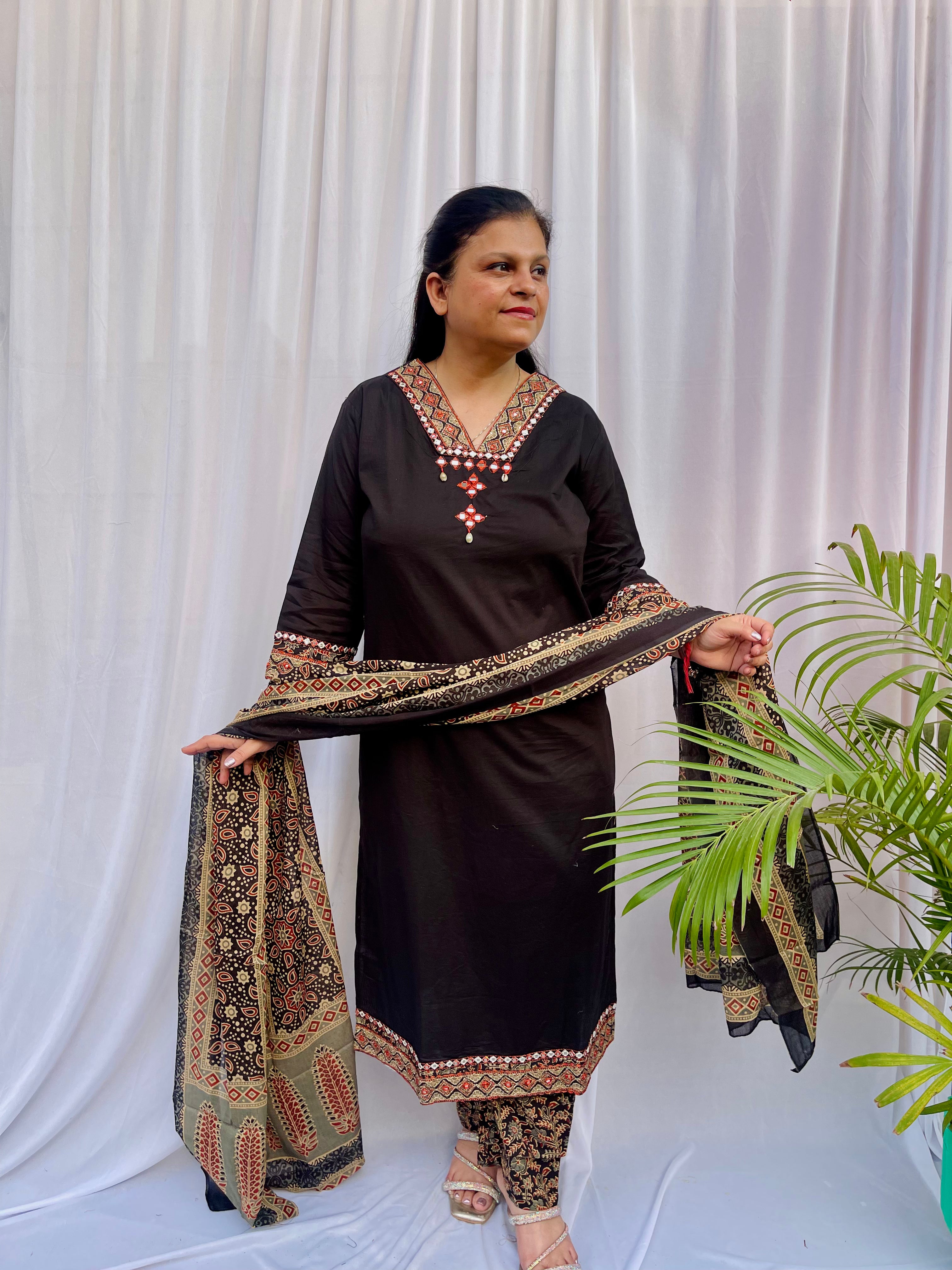 Woman wearing a black ethnic printed kurta set with matching pants and dupatta, featuring traditional motifs and a V-neck design.