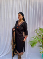 Woman wearing a black ethnic printed kurta set with matching pants and dupatta, featuring traditional motifs and a V-neck design.