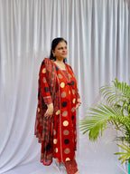 Woman wearing a rust red printed kurta set with polka dot and geometric patterns, styled with a traditional Ajrakh-inspired dupatta.