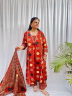 Woman wearing a rust red printed kurta set with polka dot and geometric patterns, styled with a traditional Ajrakh-inspired dupatta.