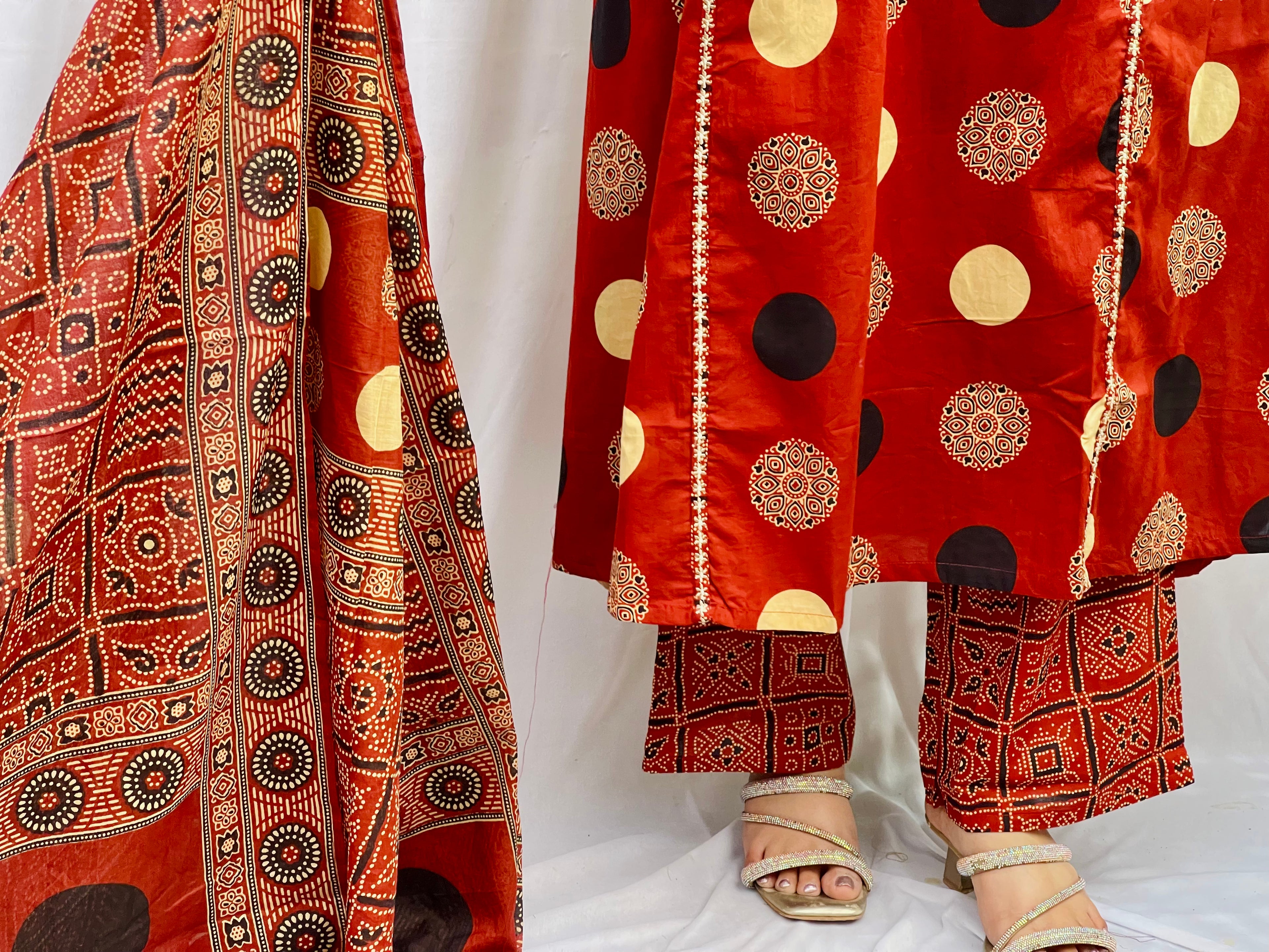 Woman wearing a rust red printed kurta set with polka dot and geometric patterns, styled with a traditional Ajrakh-inspired dupatta.