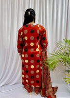 Woman wearing a rust red printed kurta set with polka dot and geometric patterns, styled with a traditional Ajrakh-inspired dupatta.
