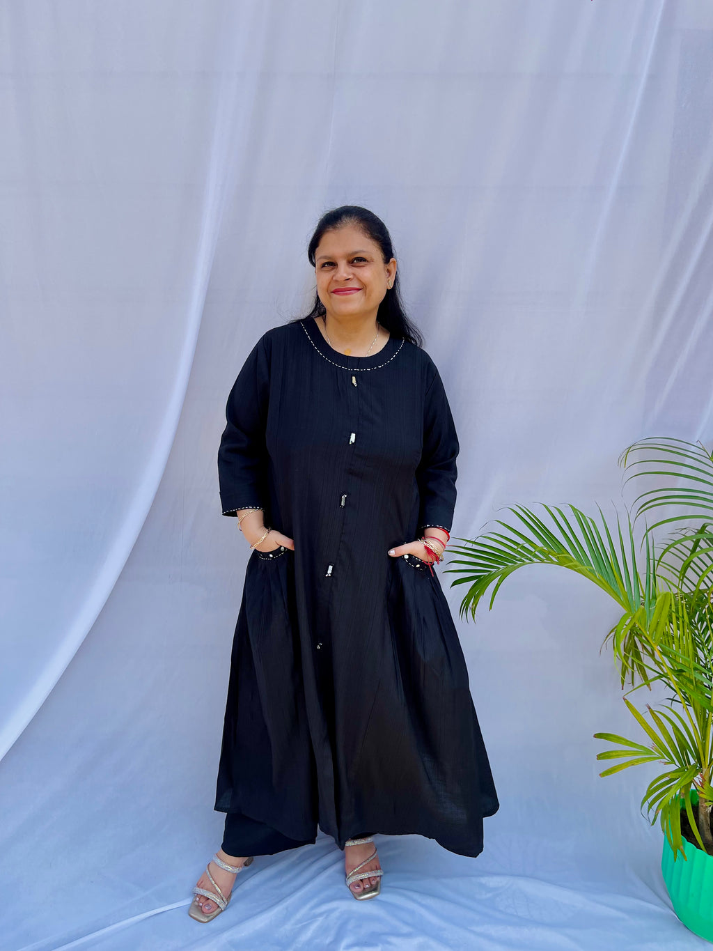Full-length view of a black self-textured long tunic with side pockets and a flared minimalist silhouette.