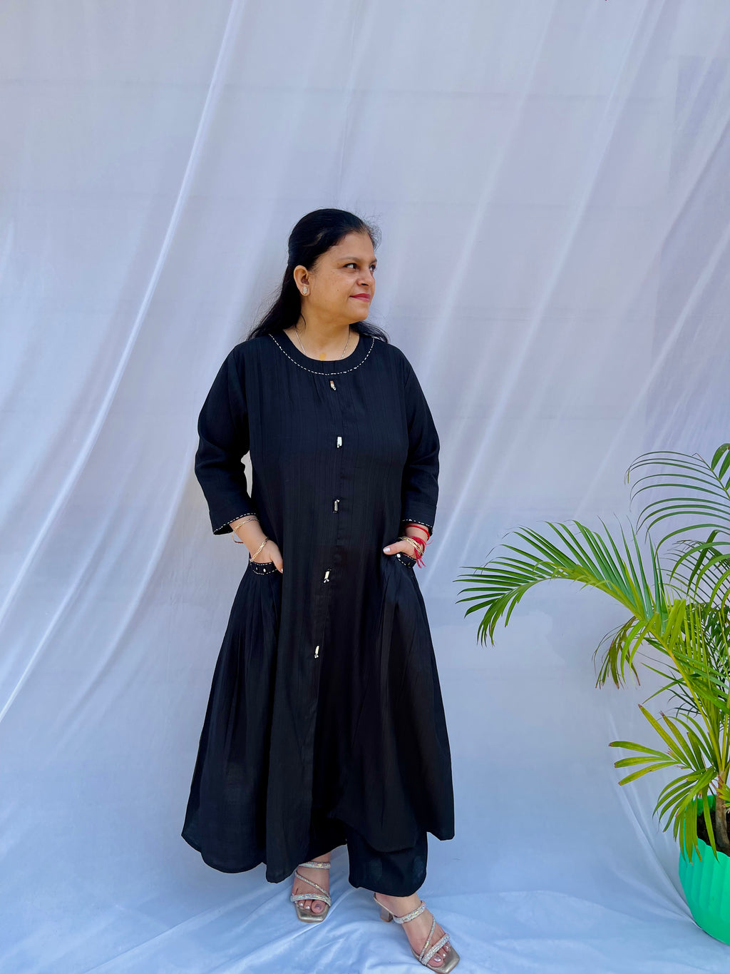 Full-length view of a black self-textured long tunic with side pockets and a flared minimalist silhouette.