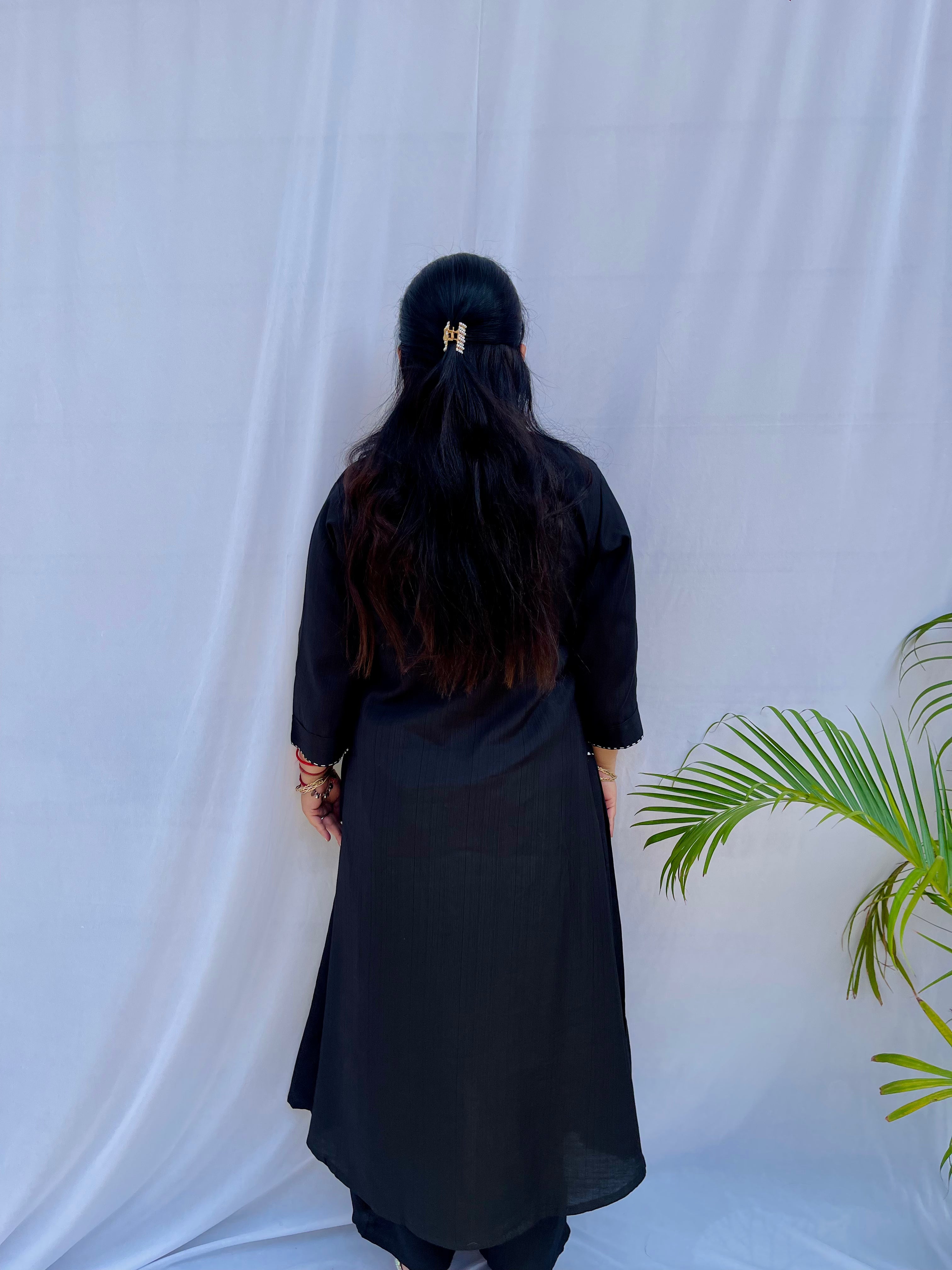 Full-length view of a black self-textured long tunic with side pockets and a flared minimalist silhouette.