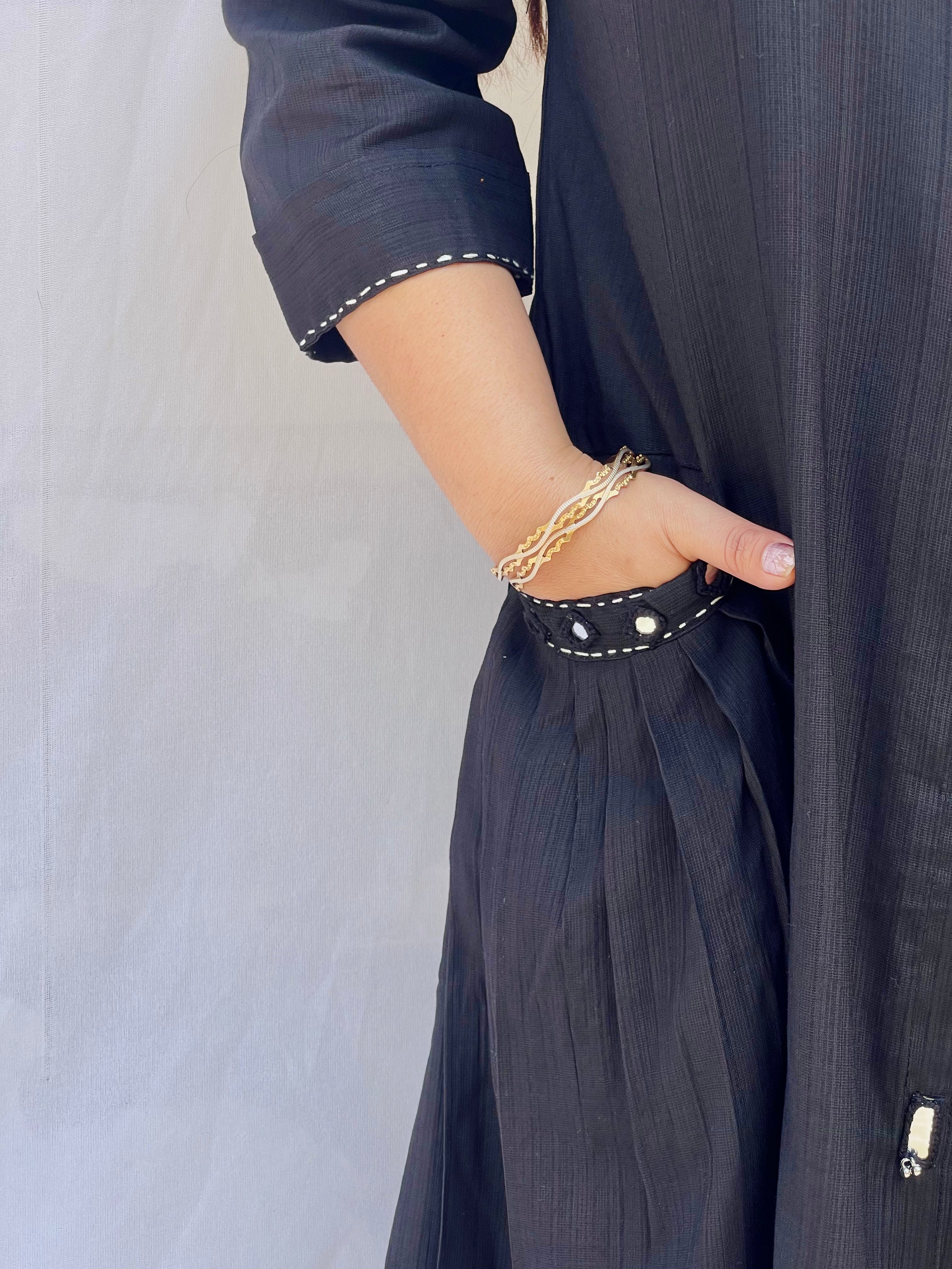 Full-length view of a black self-textured long tunic with side pockets and a flared minimalist silhouette.