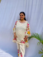 Elegant ivory white chanderi silk tunic co-ord set with large colorful floral embroidery, tassel fringe, and matching embroidered pants.