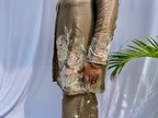 Woman in a metallic bronze silk shirt set with delicate pastel floral threadwork on the collar, hem, and cuffs.
