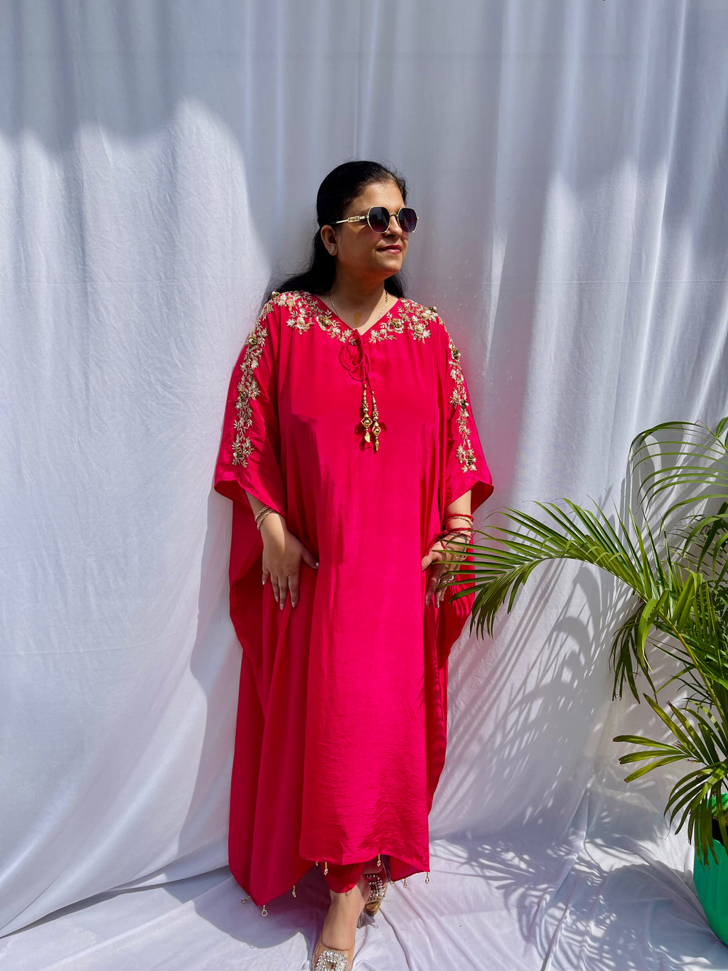 Vibrant fuchsia pink silk kaftan dress with intricate gold zardozi embroidery and crystal work on the neckline and sleeves.