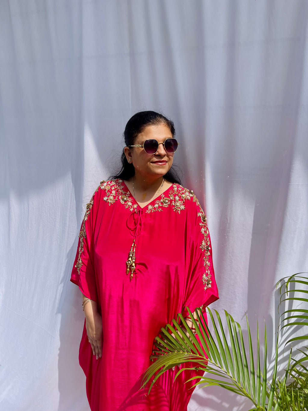 Vibrant fuchsia pink silk kaftan dress with intricate gold zardozi embroidery and crystal work on the neckline and sleeves.