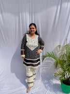 Black and white polka dot tunic featuring a V-shaped mirror work yoke, lace inserts, and matching white pants with mirror detailing.