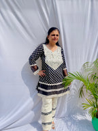 Black and white polka dot tunic featuring a V-shaped mirror work yoke, lace inserts, and matching white pants with mirror detailing.