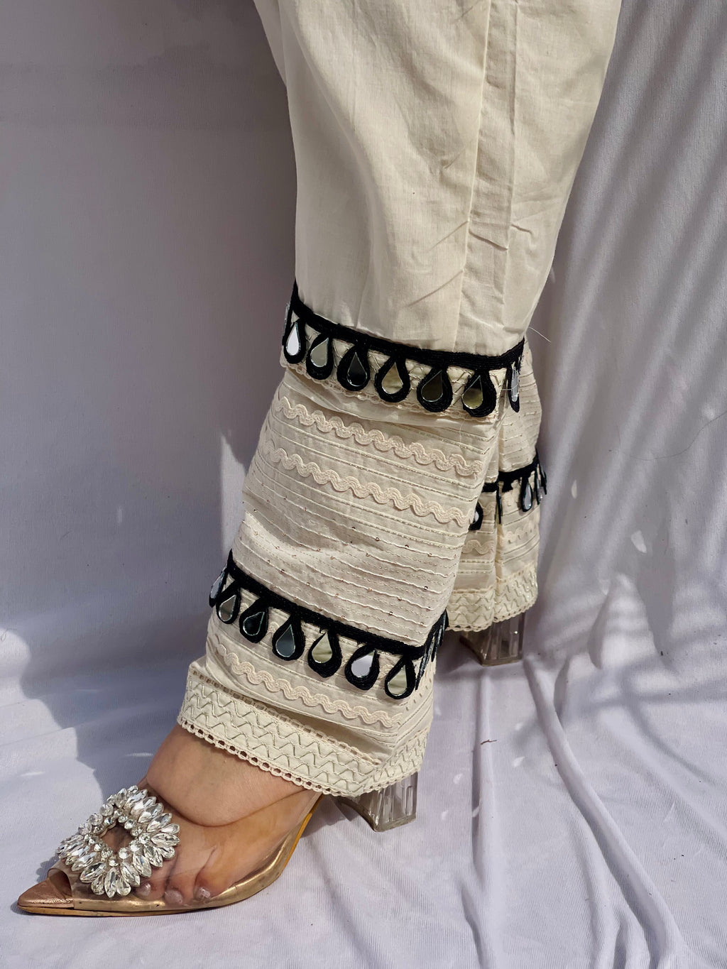 Black and white polka dot tunic featuring a V-shaped mirror work yoke, lace inserts, and matching white pants with mirror detailing.