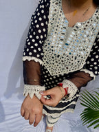 Black and white polka dot tunic featuring a V-shaped mirror work yoke, lace inserts, and matching white pants with mirror detailing.