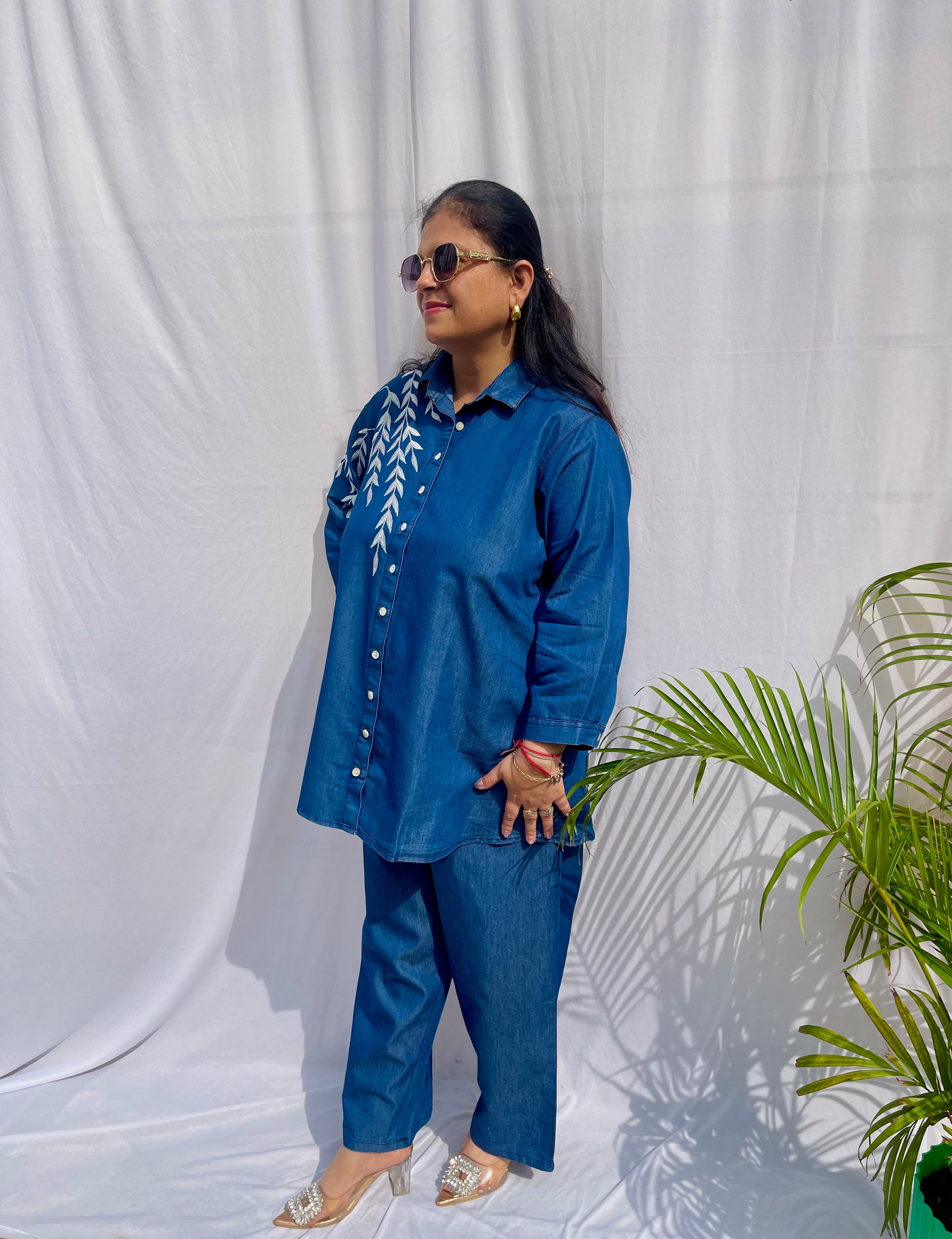 Denim-finish indigo blue shirt set with a large white leaf thread-work embroidery on the right shoulder and sleeve.
