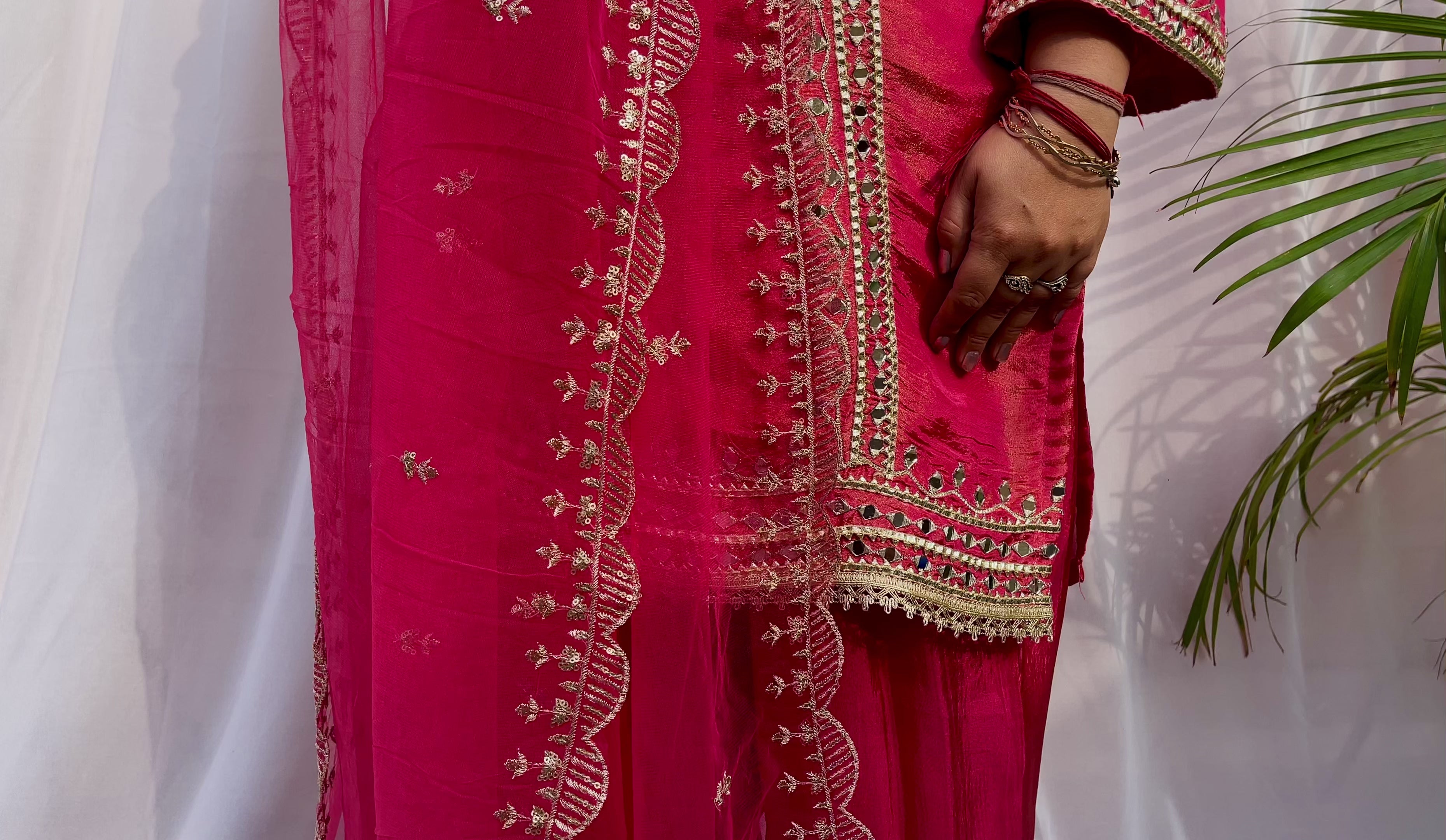 Close up of hot pink suit embroidery and dupatta border detailing with intricate threadwork