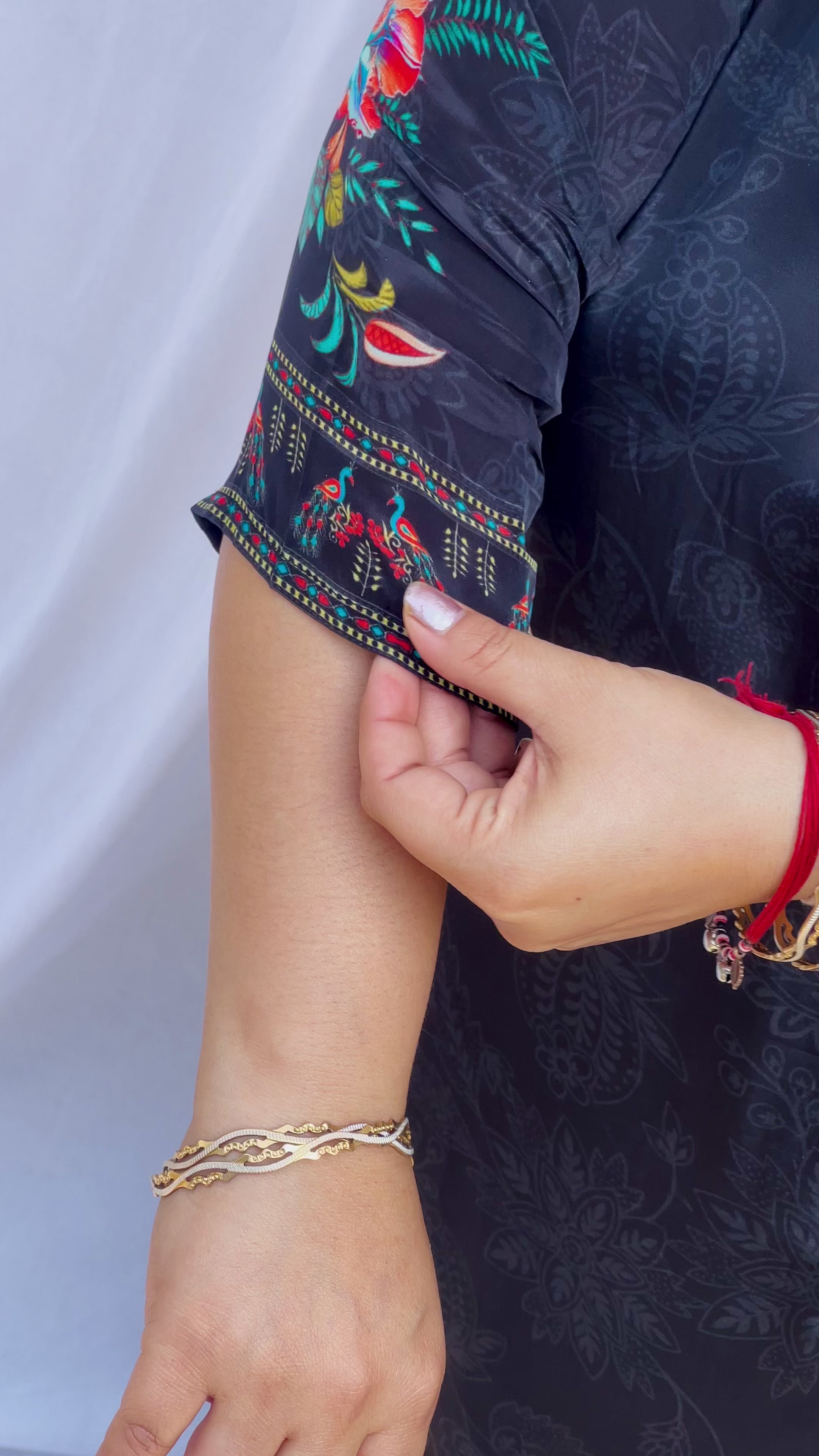 Model posing in a midnight black tunic with floral embroidered sleeves and wide-leg trousers featuring traditional elephant motifs.
