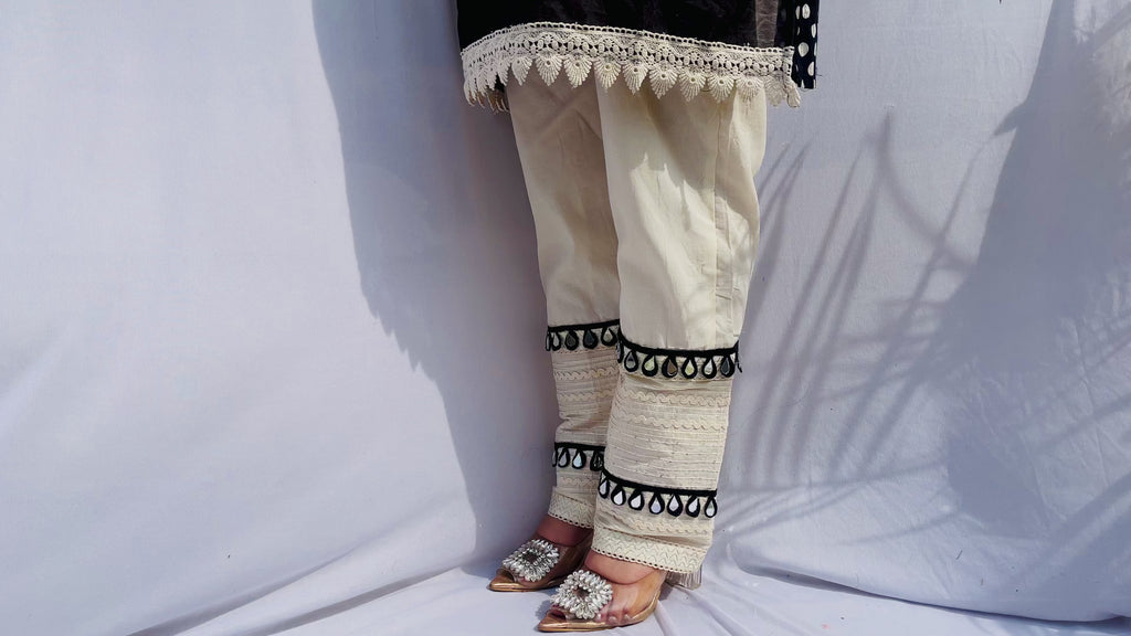 Black and white polka dot tunic featuring a V-shaped mirror work yoke, lace inserts, and matching white pants with mirror detailing.