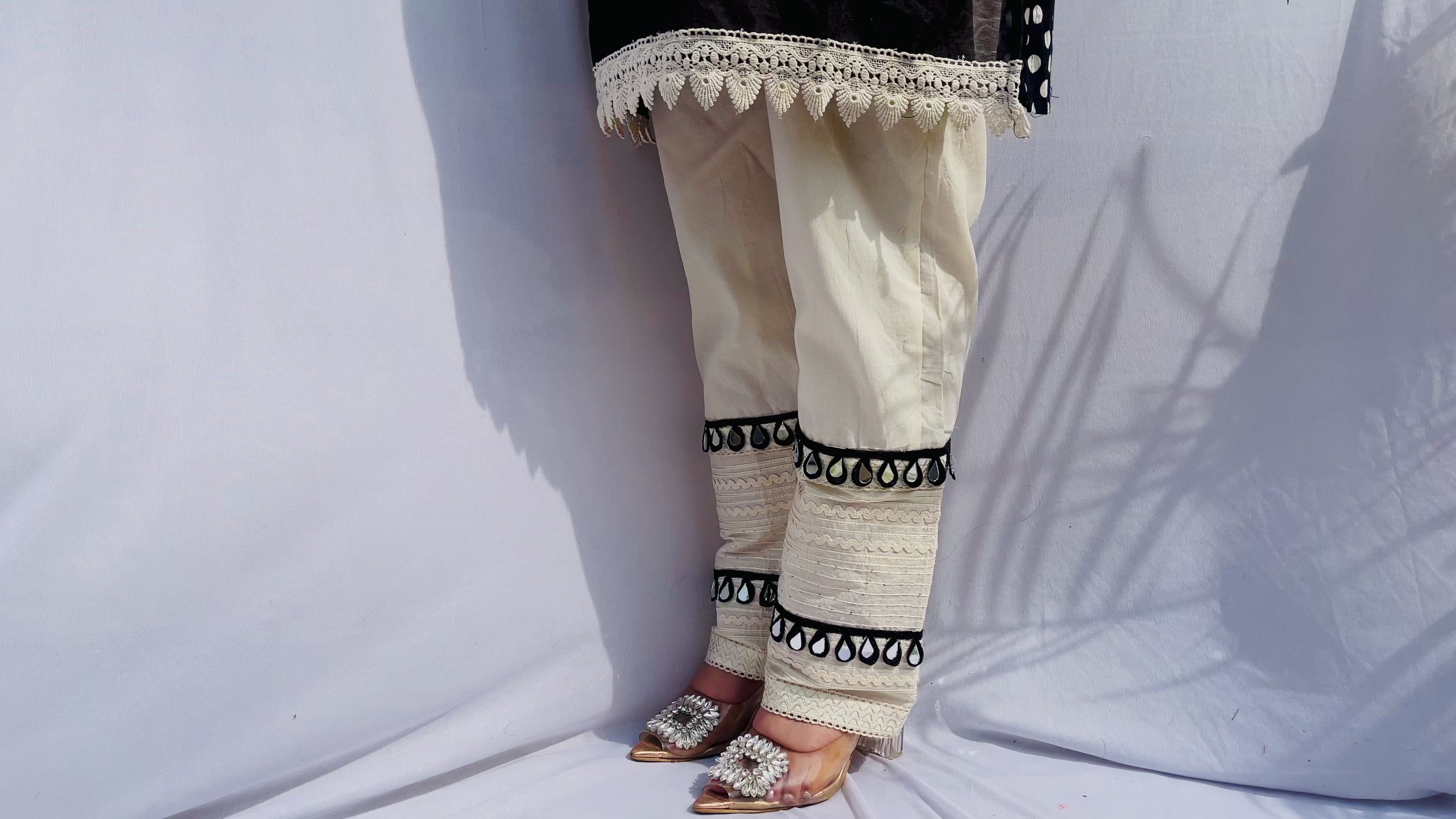Black and white polka dot tunic featuring a V-shaped mirror work yoke, lace inserts, and matching white pants with mirror detailing.