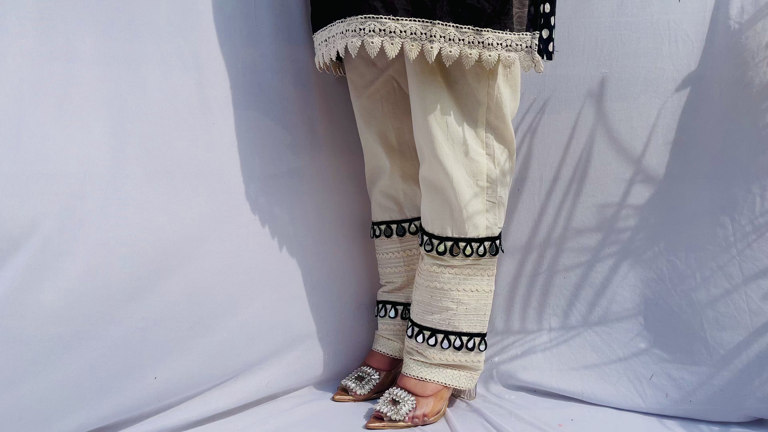 Black and white polka dot tunic featuring a V-shaped mirror work yoke, lace inserts, and matching white pants with mirror detailing.