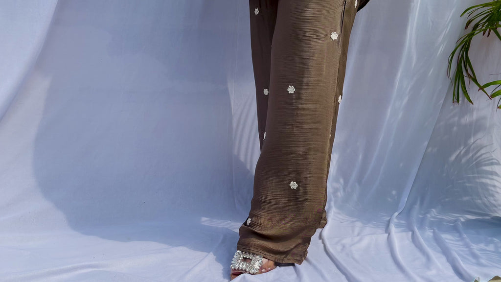 Woman in a metallic bronze silk shirt set with delicate pastel floral threadwork on the collar, hem, and cuffs.