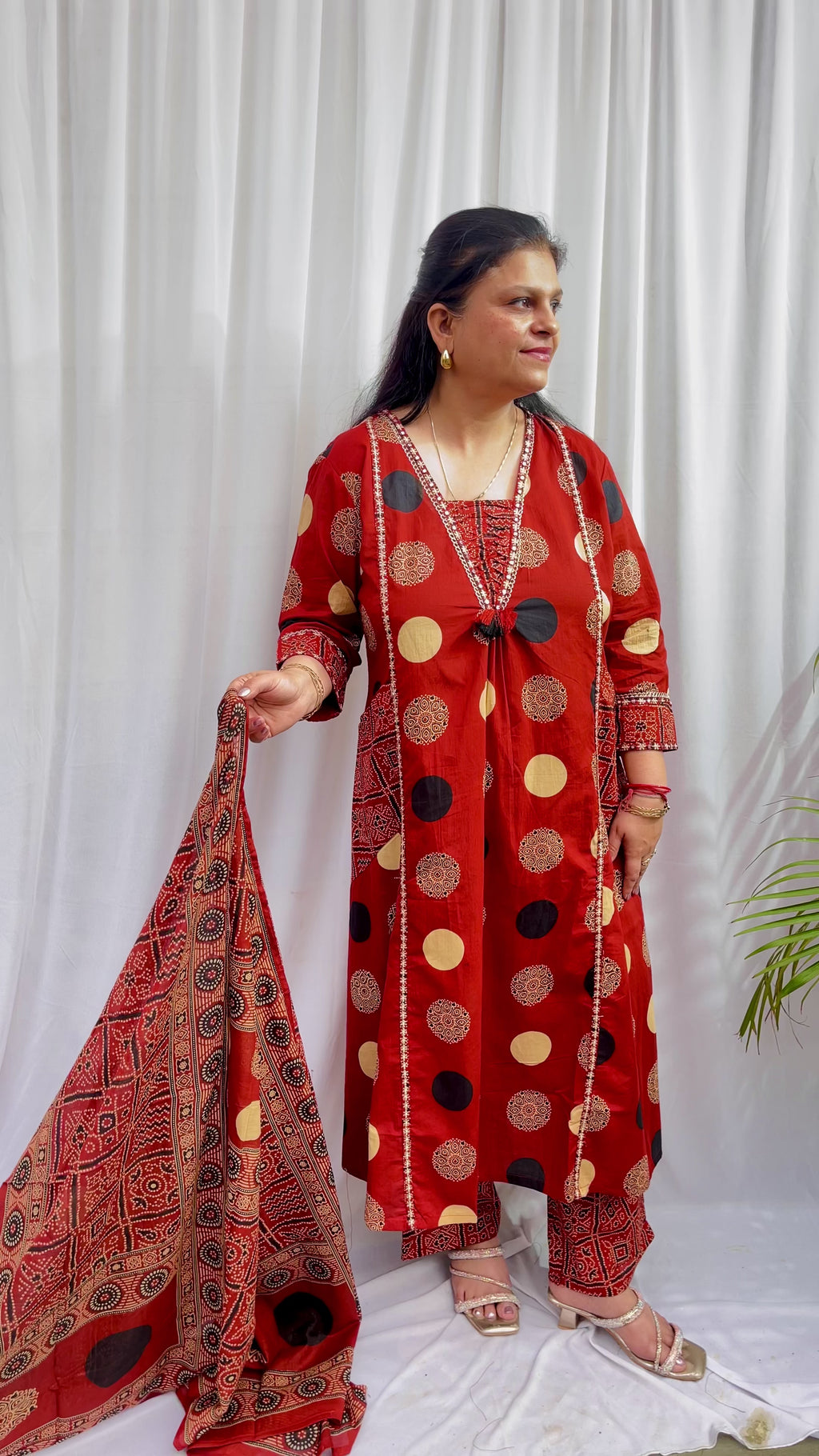 Woman wearing a rust red printed kurta set with polka dot and geometric patterns, styled with a traditional Ajrakh-inspired dupatta.