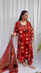 Woman wearing a rust red printed kurta set with polka dot and geometric patterns, styled with a traditional Ajrakh-inspired dupatta.