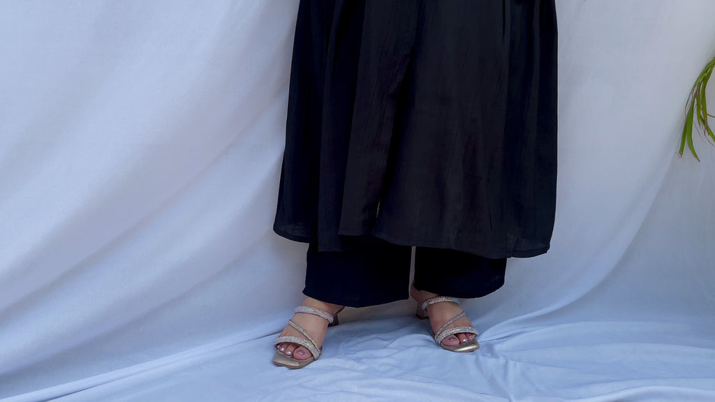 Full-length view of a black self-textured long tunic with side pockets and a flared minimalist silhouette.