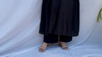 Full-length view of a black self-textured long tunic with side pockets and a flared minimalist silhouette.